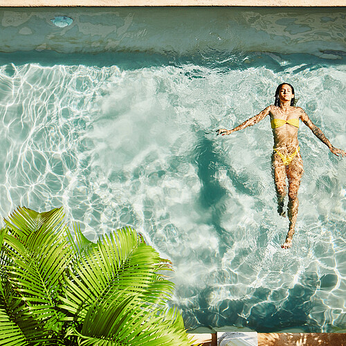 Overhead view of woman floating on her back in pool at outdoor spa